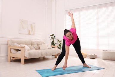 Overweight woman doing exercise at home, space for text