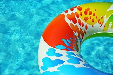 Colorful inflatable ring floating in swimming pool on sunny day. Space for text