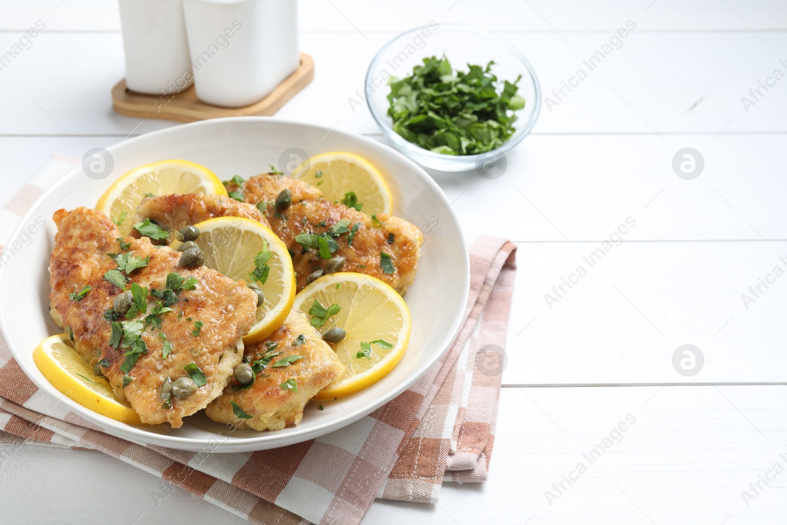 Photo of Delicious chicken piccata on white wooden table. Space for text