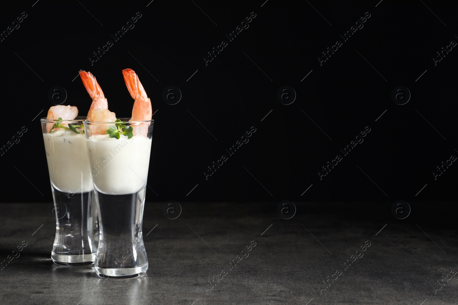 Photo of Glasses with boiled shrimps and sauce on dark background