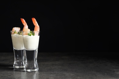 Glasses with boiled shrimps and sauce on dark background