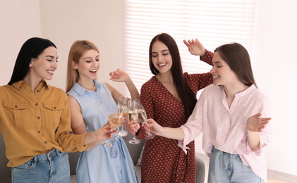 Photo of Beautiful young ladies clinking glasses of champagne at home. Women's Day
