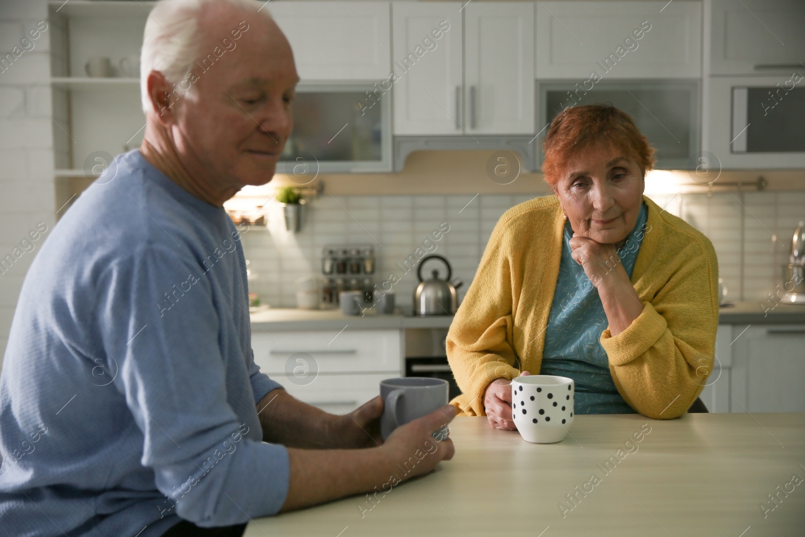 Photo of Elderly couple drinking tea at table in kitchen