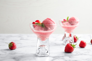 Photo of Delicious pink ice cream served with strawberries in dessert bowls on marble table