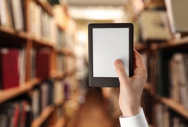 Woman holding e-book reader in library, closeup and space for text