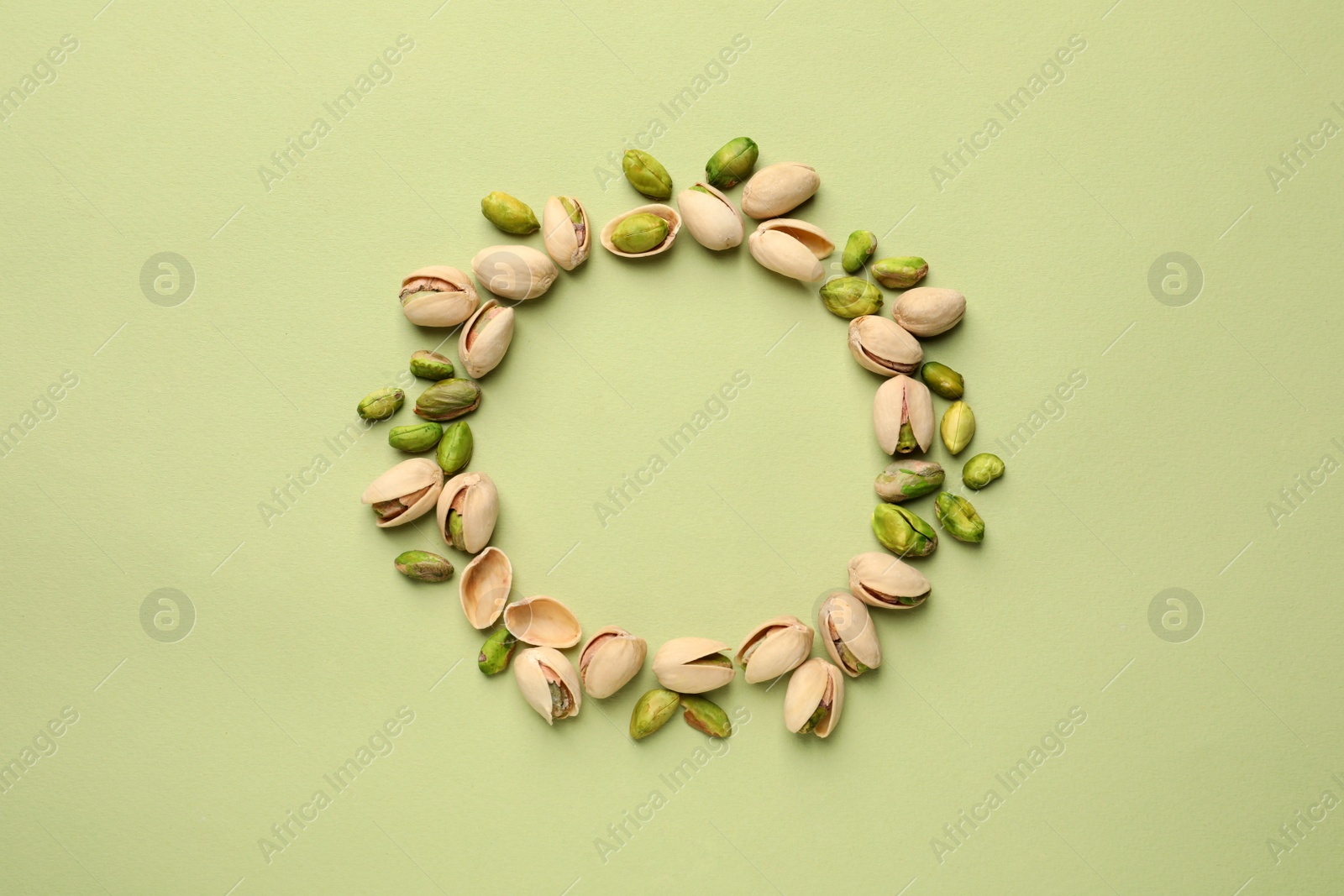 Photo of Round frame made of organic pistachio nuts on color background, top view. Space for text
