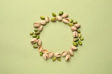 Photo of Round frame made of organic pistachio nuts on color background, top view. Space for text