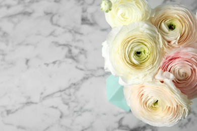 Beautiful ranunculus flowers in vase on marble table. Space for text