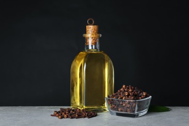 Essential oil and dried cloves on grey stone table
