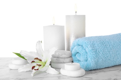 Photo of Composition with towel, spa stones and candles on marble table against white background