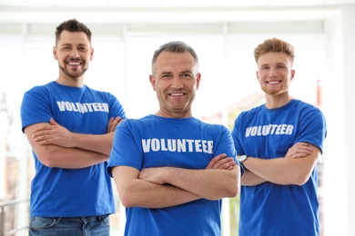 Photo of Portrait of happy male volunteers in uniform indoors