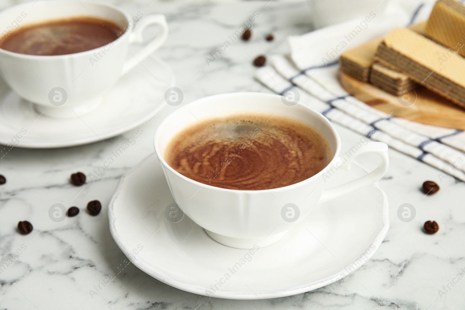 Photo of Delicious coffee and wafers for breakfast on white marble table