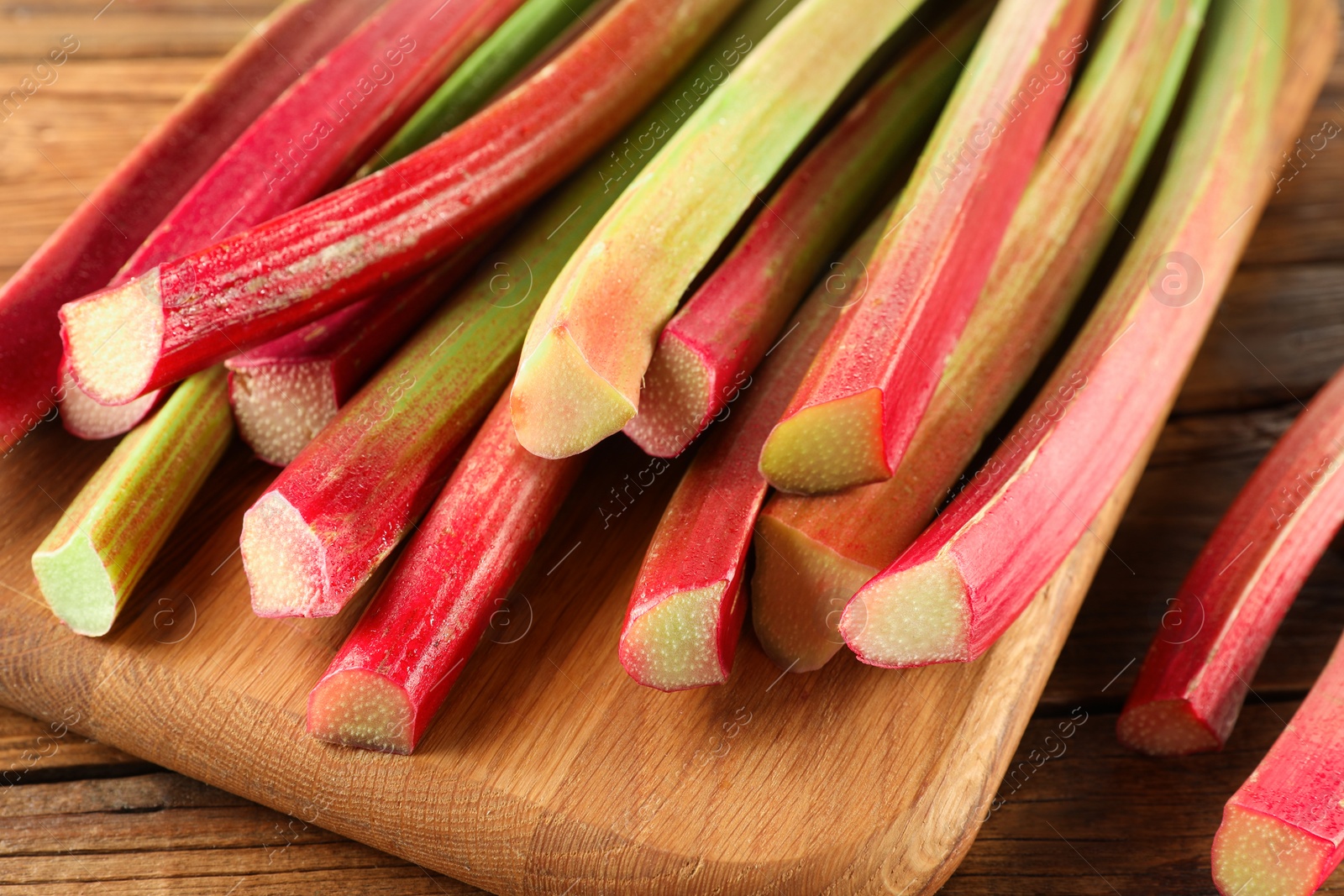 Photo of Many cut rhubarb stalks on wooden table, closeup