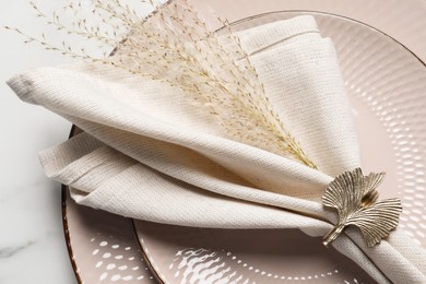 Photo of Plates with fabric napkin, decorative ring and branches on white marble table, top view