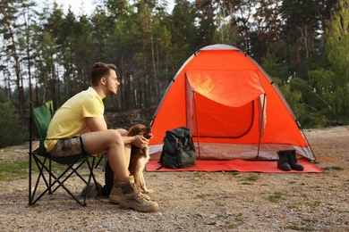 Young man with dog near camping tent outdoors