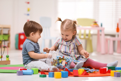 Photo of Cute little children playing together on floor at home