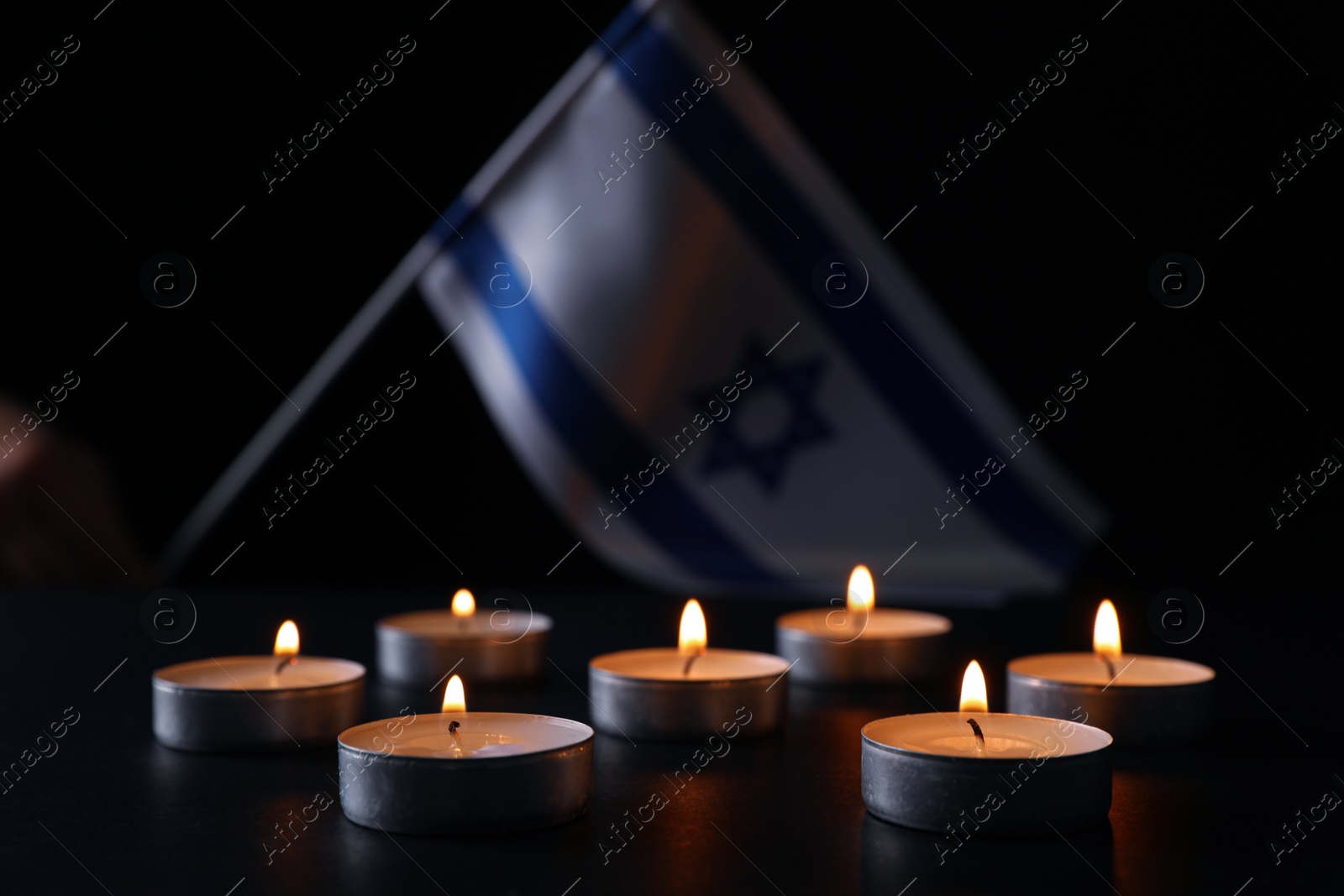 Photo of Burning candles on black table. Holocaust memory day