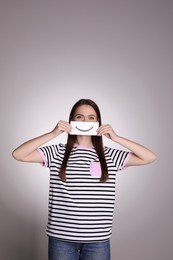 Woman holding sheet of paper with smile on grey background