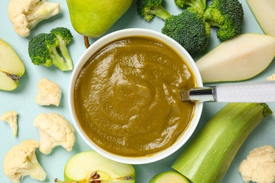 Healthy baby food and ingredients on light blue background, flat lay