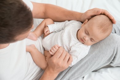 Father with his cute sleeping baby on bed, above view