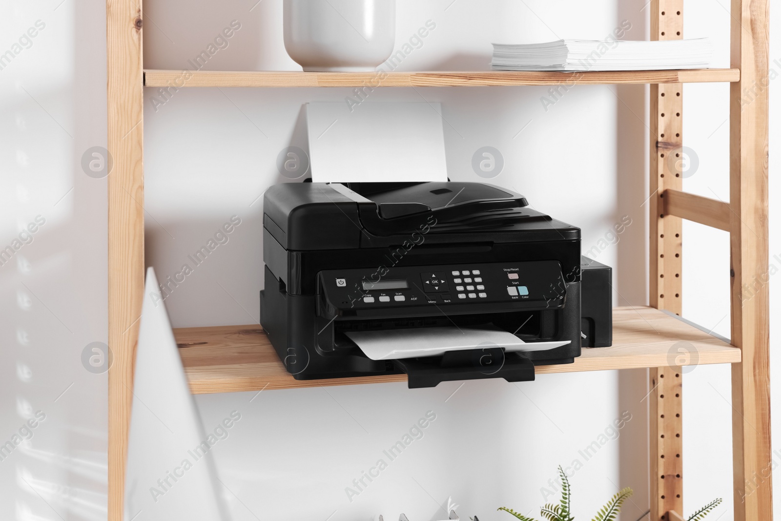 Photo of Modern printer with paper on wooden shelf in home office