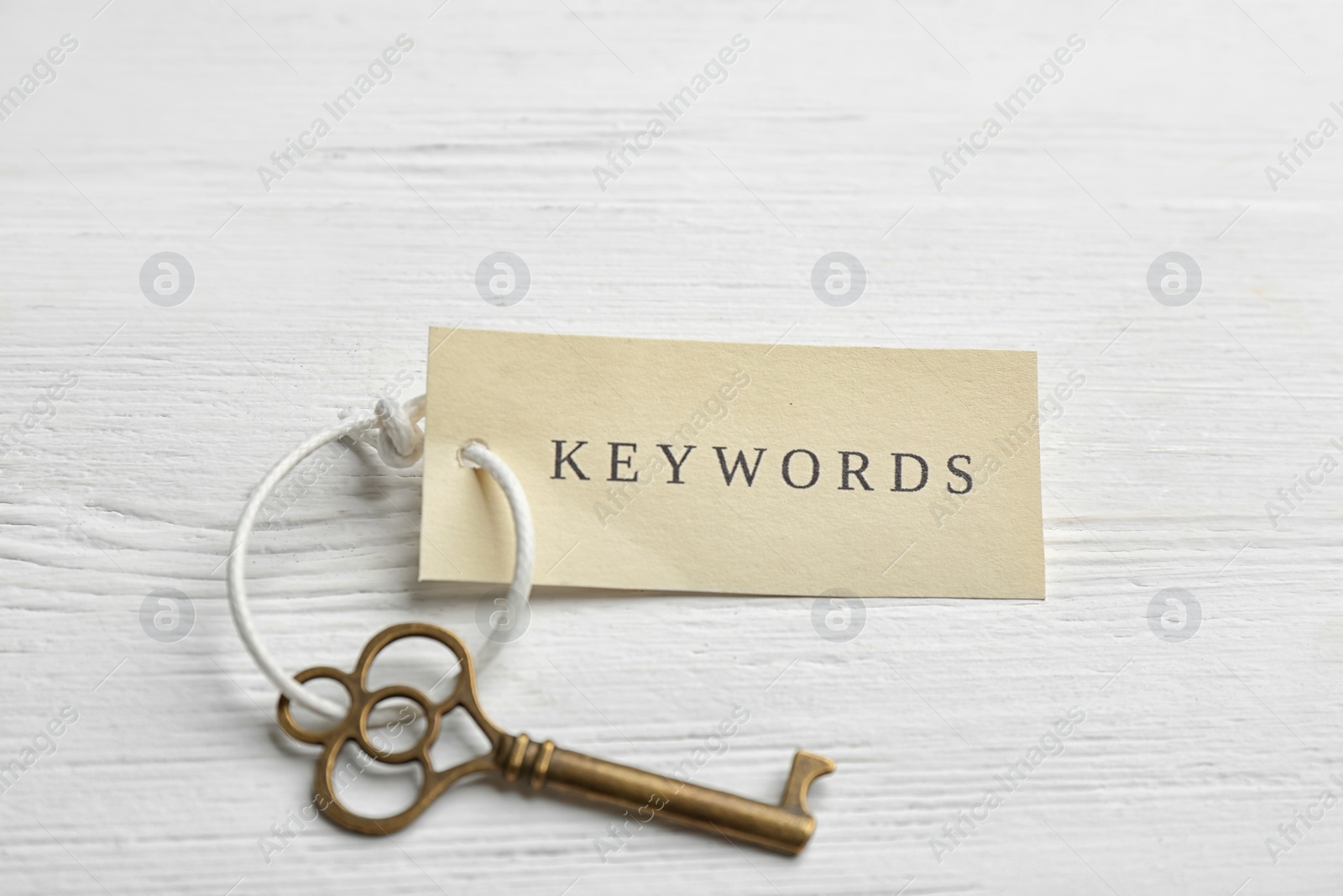 Photo of Key with tag KEYWORDS on white wooden background