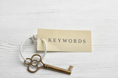 Photo of Key with tag KEYWORDS on white wooden background