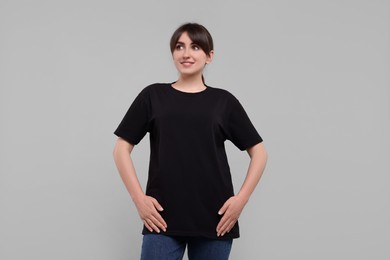 Photo of Smiling woman in stylish black t-shirt on light grey background