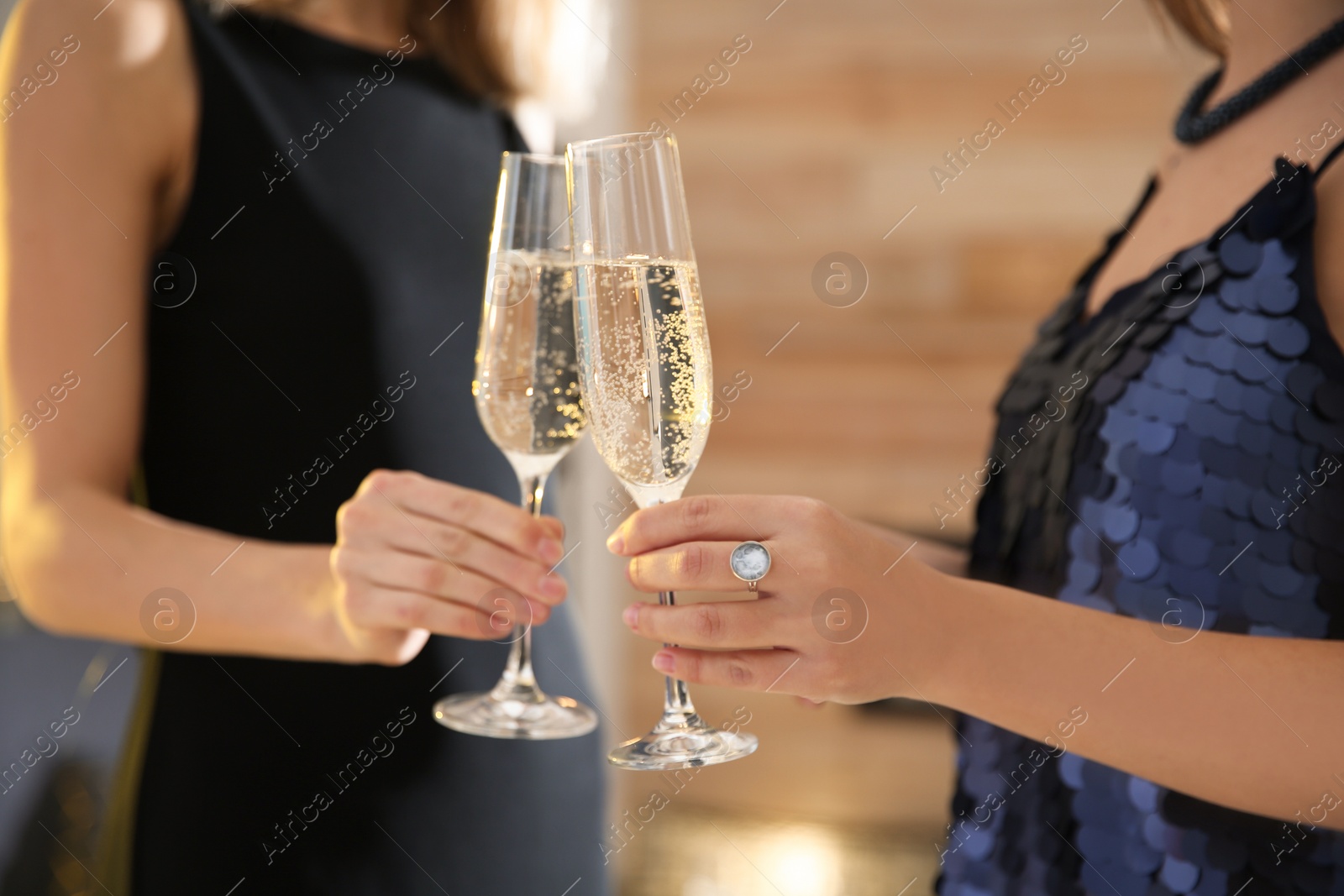 Photo of Friends clinking glasses with champagne at party indoors, closeup