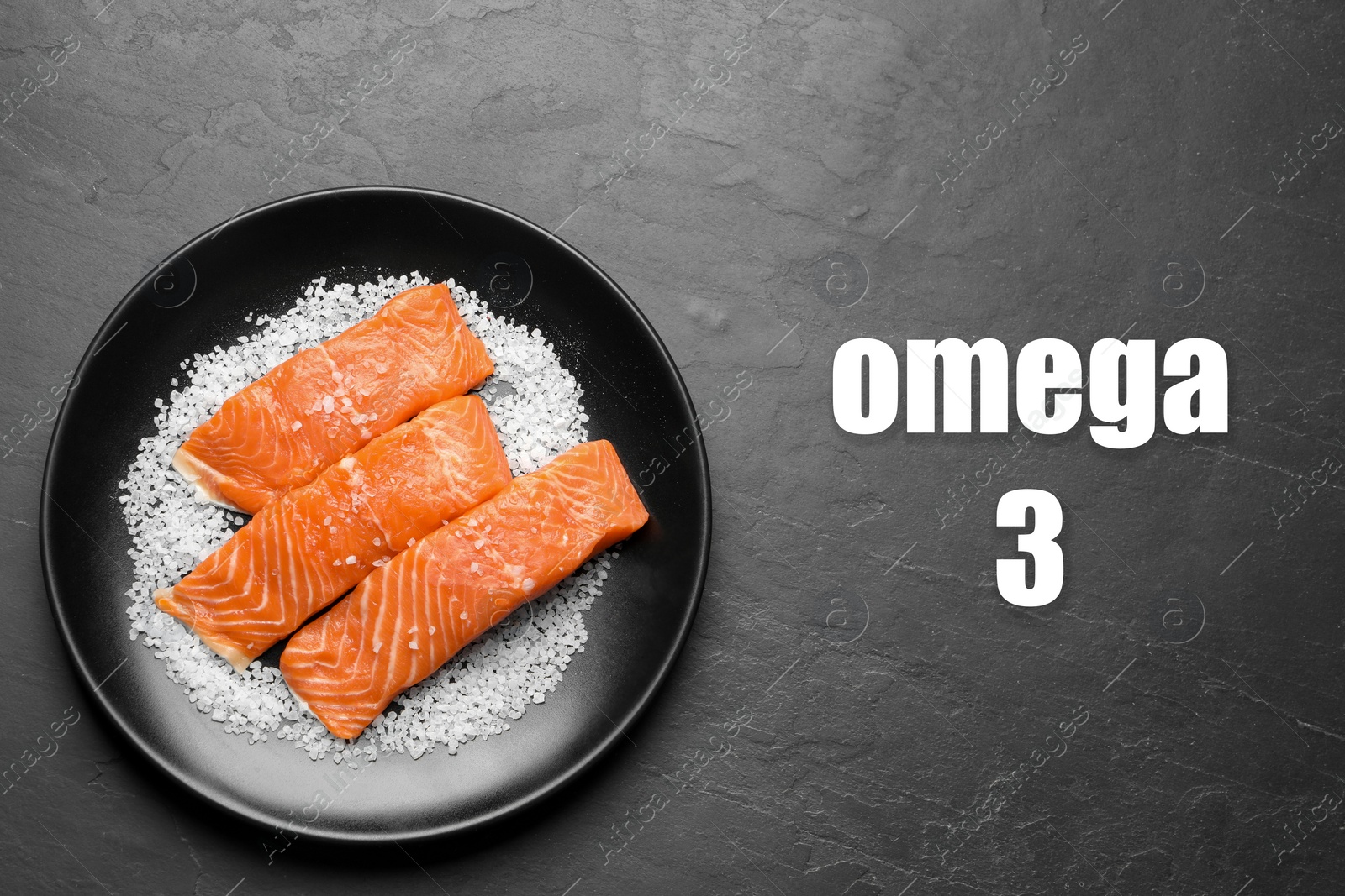 Image of Omega 3. Plate with fresh cut salmon and salt on black table, top view