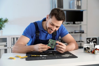 Male technician repairing hard drive at table indoors