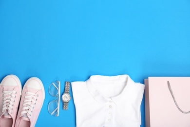 Photo of Stylish flat lay composition with shopping bag and clothing on color background