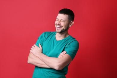 Handsome man laughing on red background. Funny joke