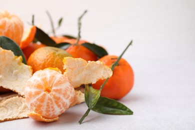 Photo of Many fresh ripe tangerines and leaves on white table, space for text, closeup