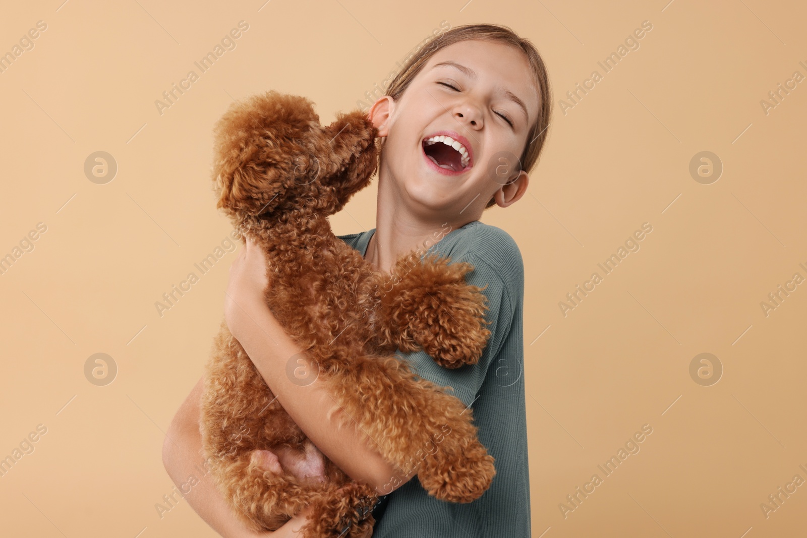 Photo of Emotional little child with cute puppy on beige background. Lovely pet