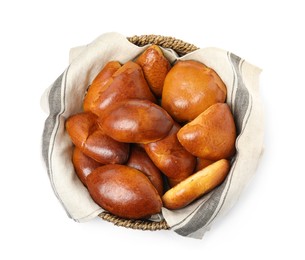 Wicker basket with delicious baked pirozhki on white background, top view