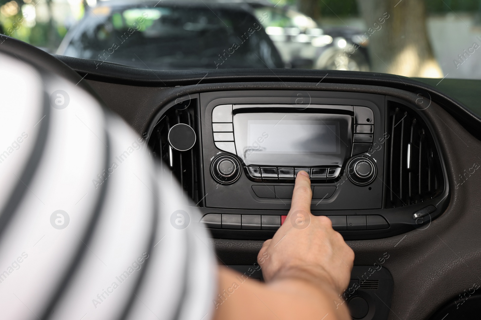 Photo of Choosing favorite radio. Man pressing button on vehicle audio in car, closeup