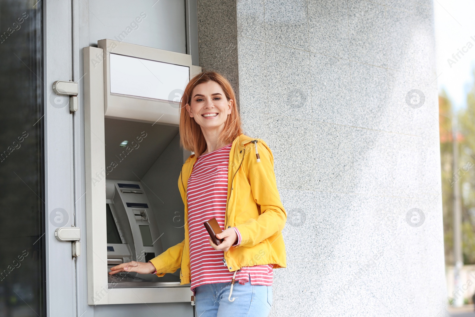 Photo of Beautiful woman using cash machine for money withdrawal outdoors. Space for text