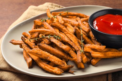 Photo of Sweet tasty potato fries and ketchup on table, closeup