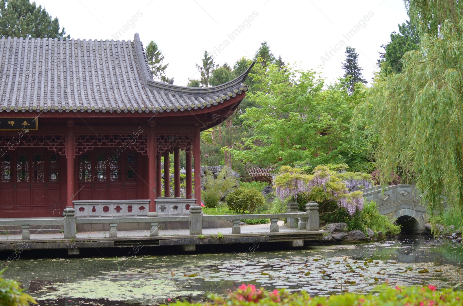 Photo of HAREN, NETHERLANDS - MAY 23, 2022: Beautiful view of oriental building near pond in Chinese garden