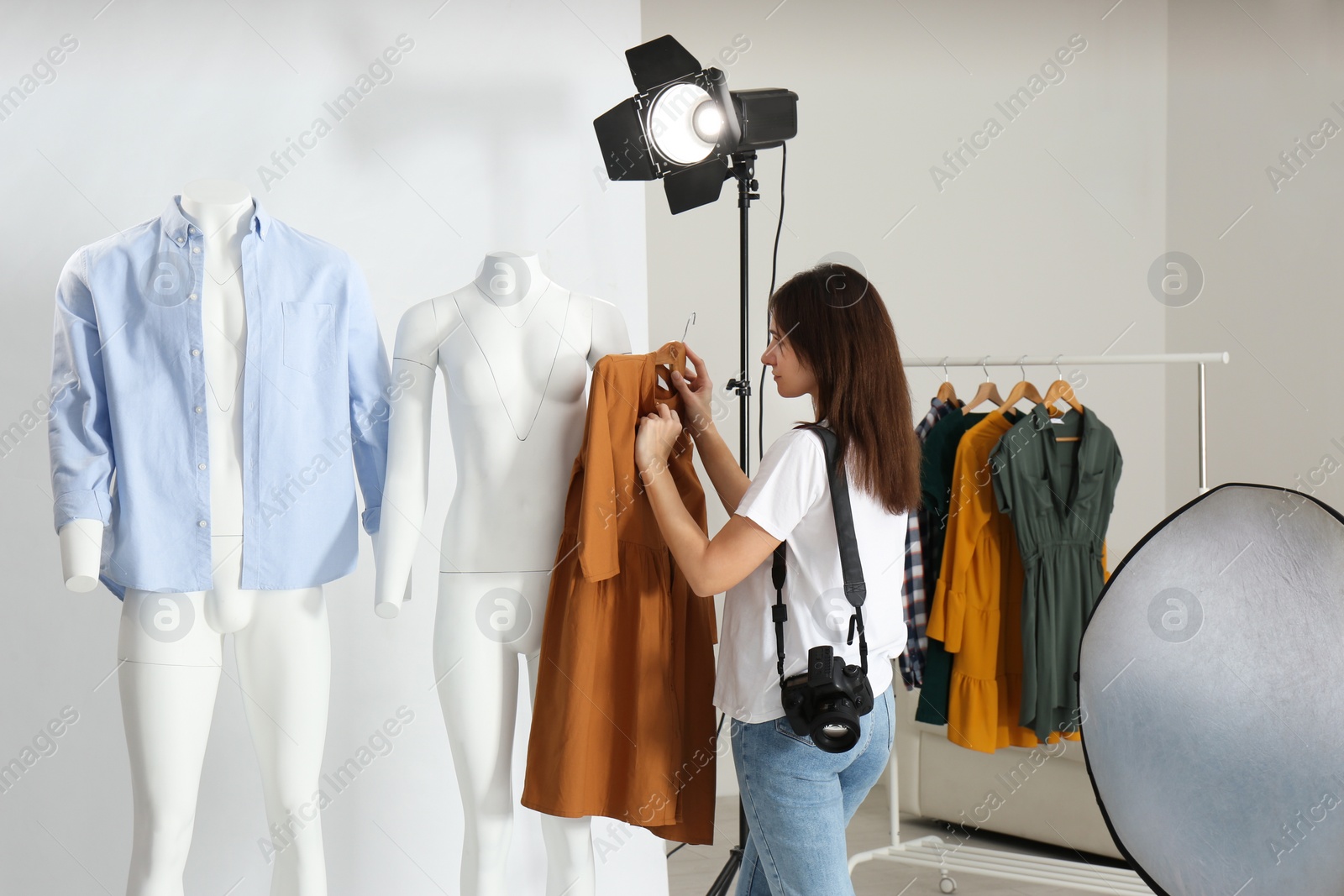 Photo of Woman putting clothes on ghost mannequins in professional photo studio