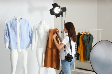 Woman putting clothes on ghost mannequins in professional photo studio