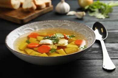 Photo of Dish with fresh homemade chicken soup on wooden table