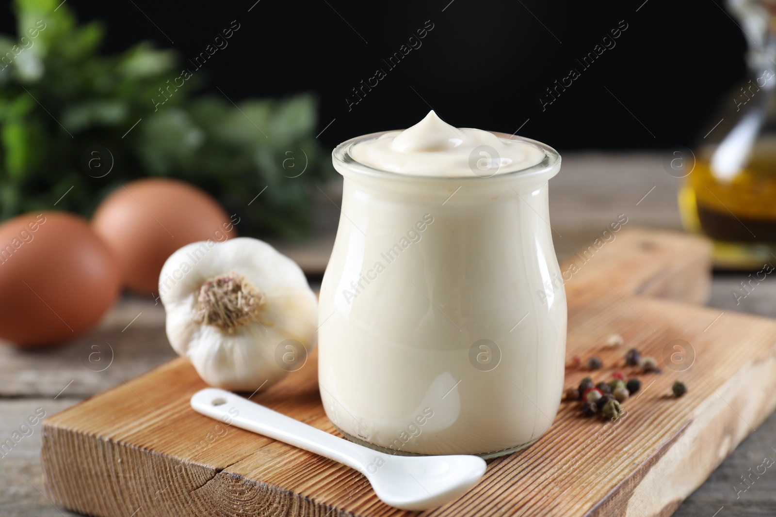 Photo of Fresh mayonnaise sauce in glass jar and ingredients on wooden table, closeup