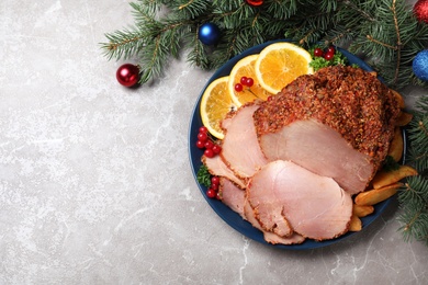 Photo of Flat lay composition with plate of Christmas ham on grey table. Space for text