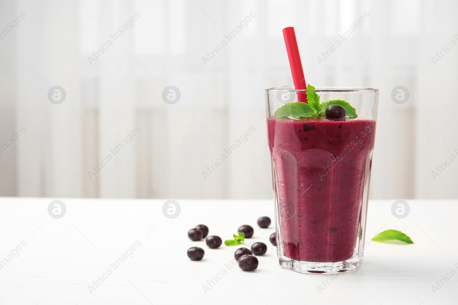 Photo of Glass with delicious acai smoothie on table