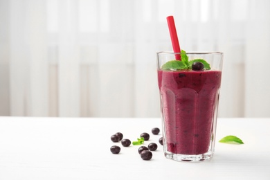 Glass with delicious acai smoothie on table