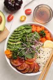 Delicious vegan bowl with avocados, carrots and tomatoes on light grey table, flat lay