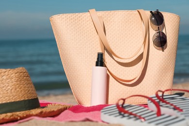 Straw hat, bag and other beach items on pink towel