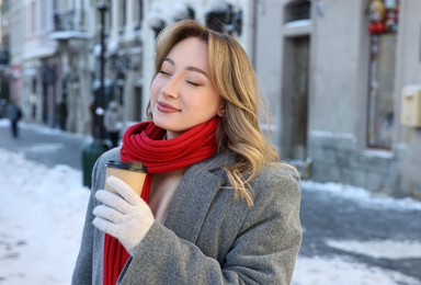 Photo of Portrait of charming woman with coffee on city street in winter